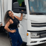Mulher sorrindo segurando retrovisor de caminhão