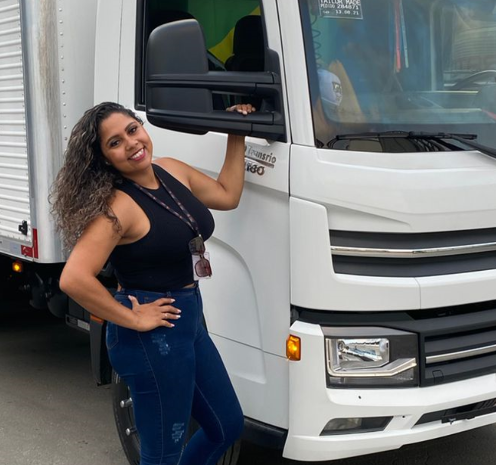 Mulher sorrindo segurando retrovisor de caminhão